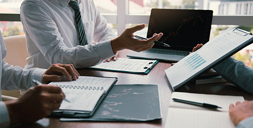 Partner colleagues are talking about the results in the document on hand and together analyze the work data about the company's financial statements.